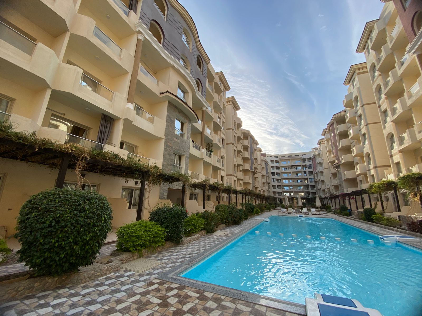 Luxury swimming pool at Florenza Khamsin surrounded by palm trees and elegant resort-style architecture.